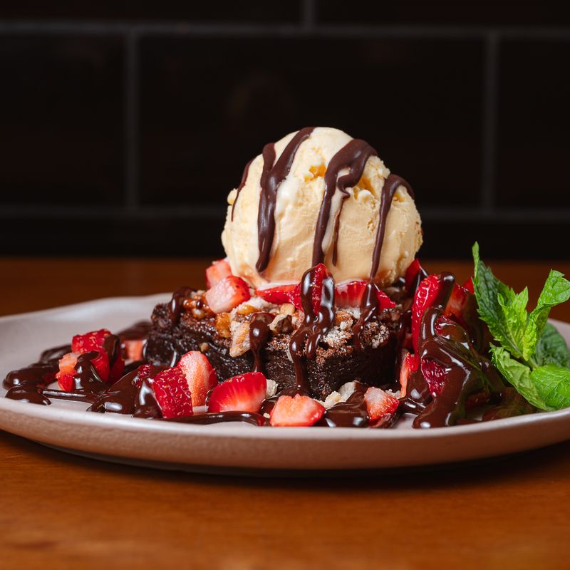 Brownie com sorvete, morangos e calda de chocolate
