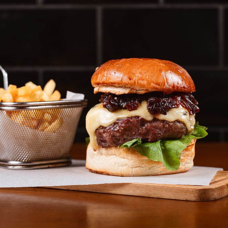 Burger no pão brioche com queijo e cebola caramelizada, e batatas fritas