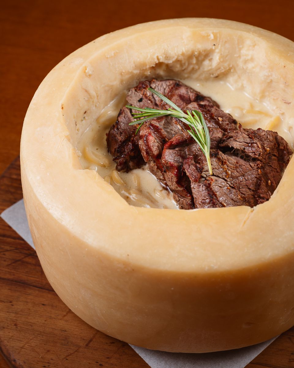 Massa grano duro aos 4 queijos com medalhões de filé, servida dentro do queijo parmesão